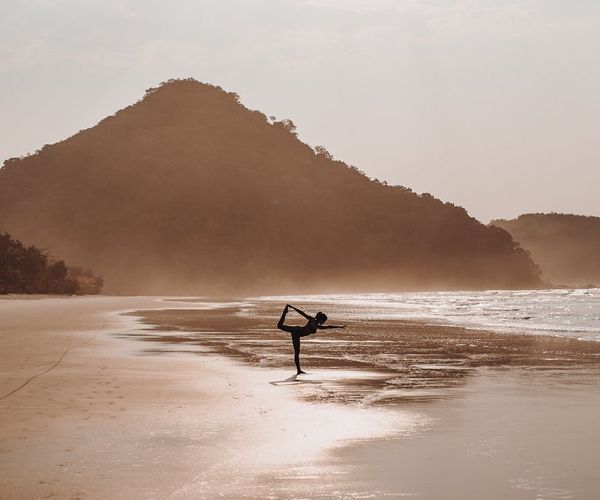 Silhouette of a woman in a warrior yoga pose during sunrise.